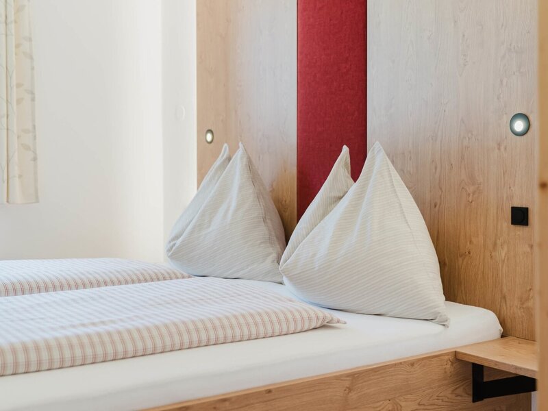 A cozy double bed with inviting striped bedding and a warm wooden headboard at the farmhouse.