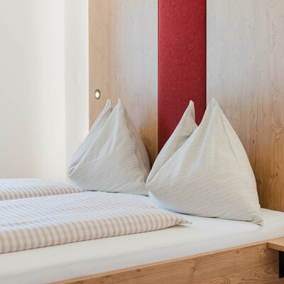 A cozy double bed with inviting striped bedding and a warm wooden headboard at the farmhouse.