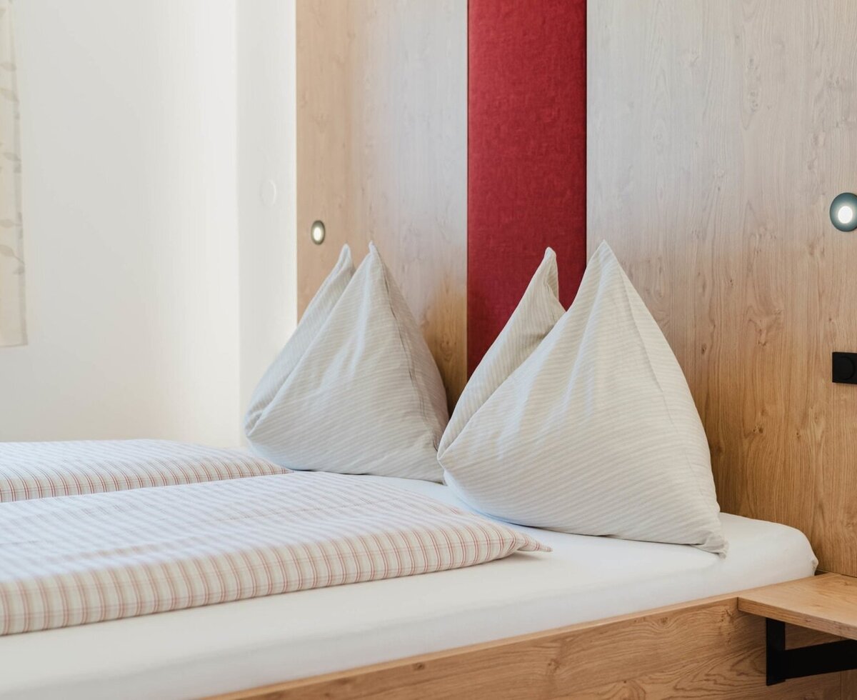 A cozy double bed with inviting striped bedding and a warm wooden headboard at the farmhouse.