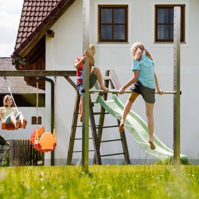The farm house features a large outdoor playground with swings, a slide, and climbing equipment for children.