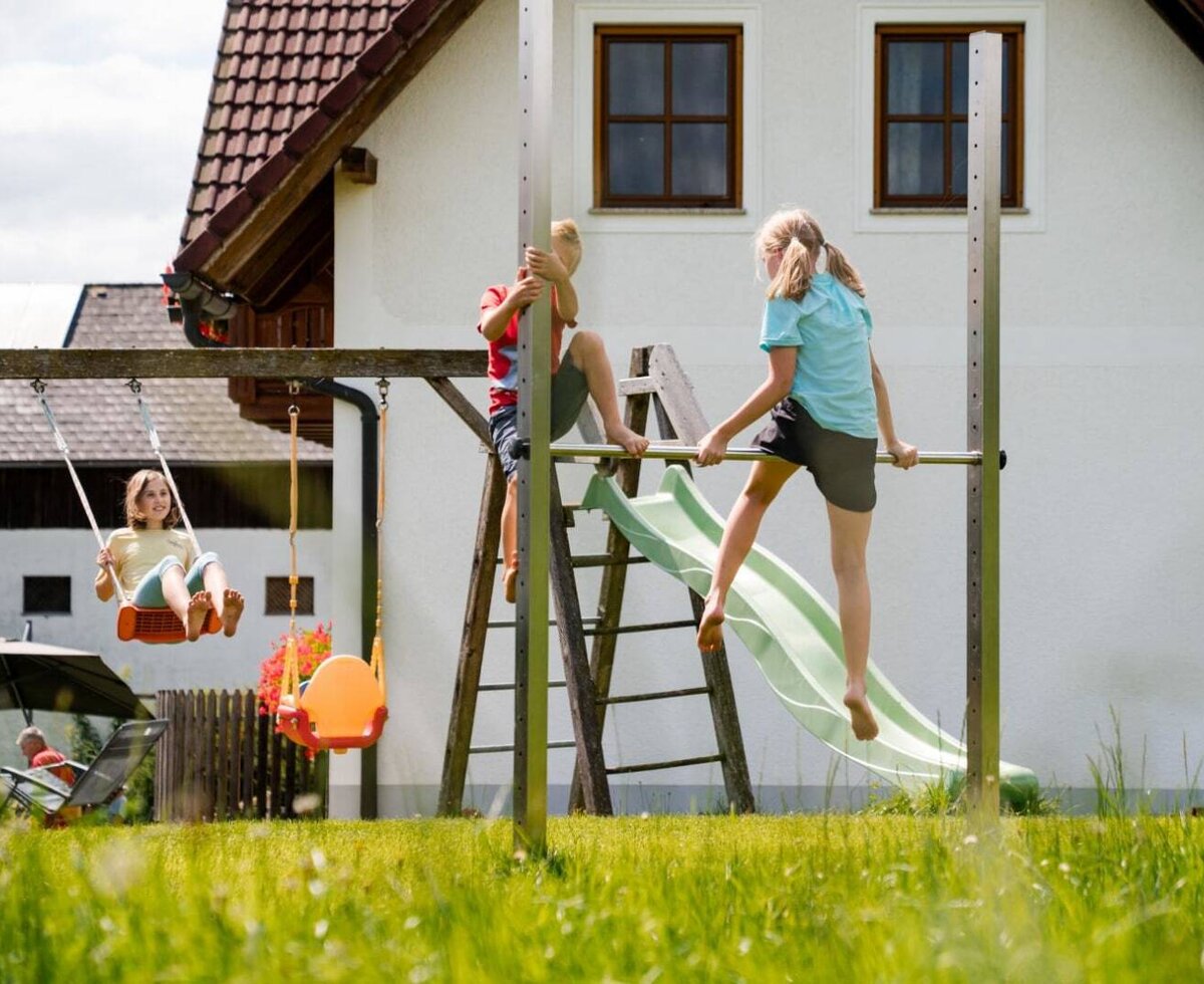 The farm house features a large outdoor playground with swings, a slide, and climbing equipment for children.