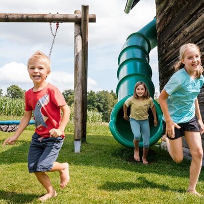 The Farm House provides an outdoor playground with a slide and a swing for children.
