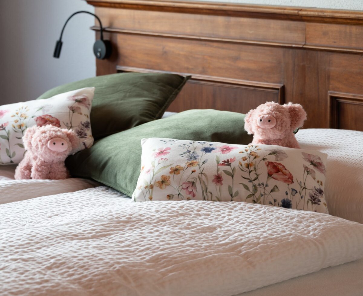 Bedroom in the Farm House with a wooden headboard, white bedding, and an adjustable reading lamp.