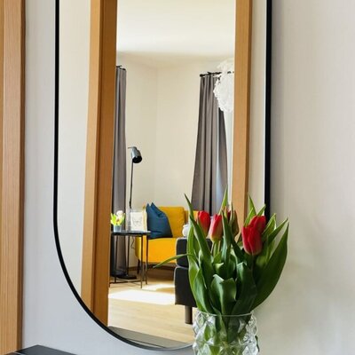 Farm House entryway with a full-length mirror, coat hooks, and shoe storage, reflecting the living area.