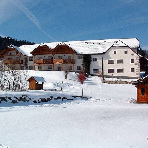 The Farm House exterior in winter, featuring multiple buildings with wooden balconies and snow-covered grounds. The Farm House exterior in winter, featuring multiple buildings with wooden balconies and snow-covered grounds.