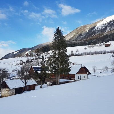 The Farm House set in a snowy landscape with mountains in the background.