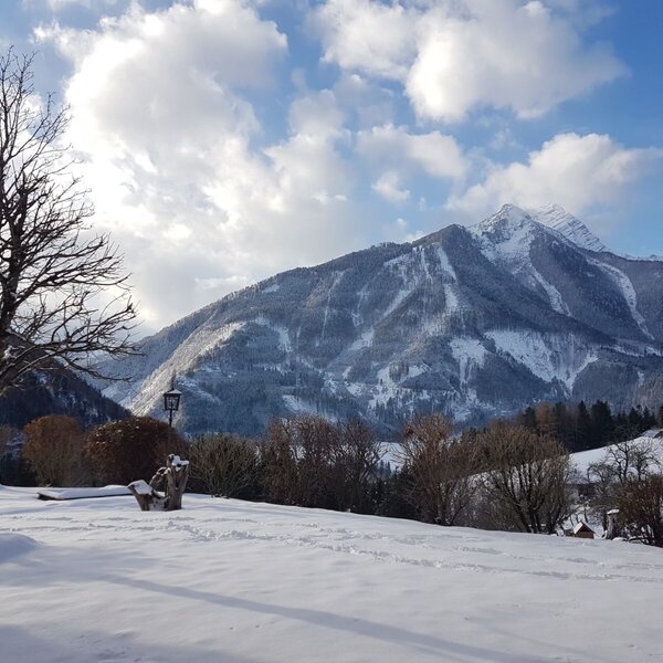 The Farm House's snow-covered outdoor play-area, featuring a slide, is set against a backdrop of snow-capped mountains.