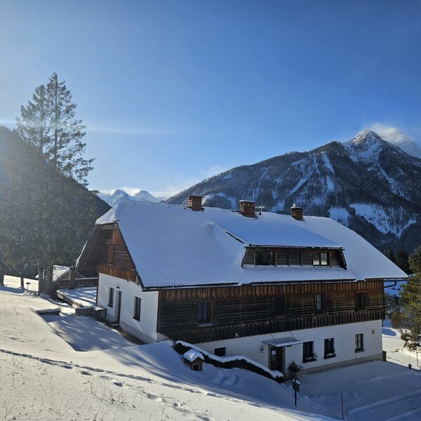 The snow-covered farmhouse with a traditional wooden facade and mountain views.