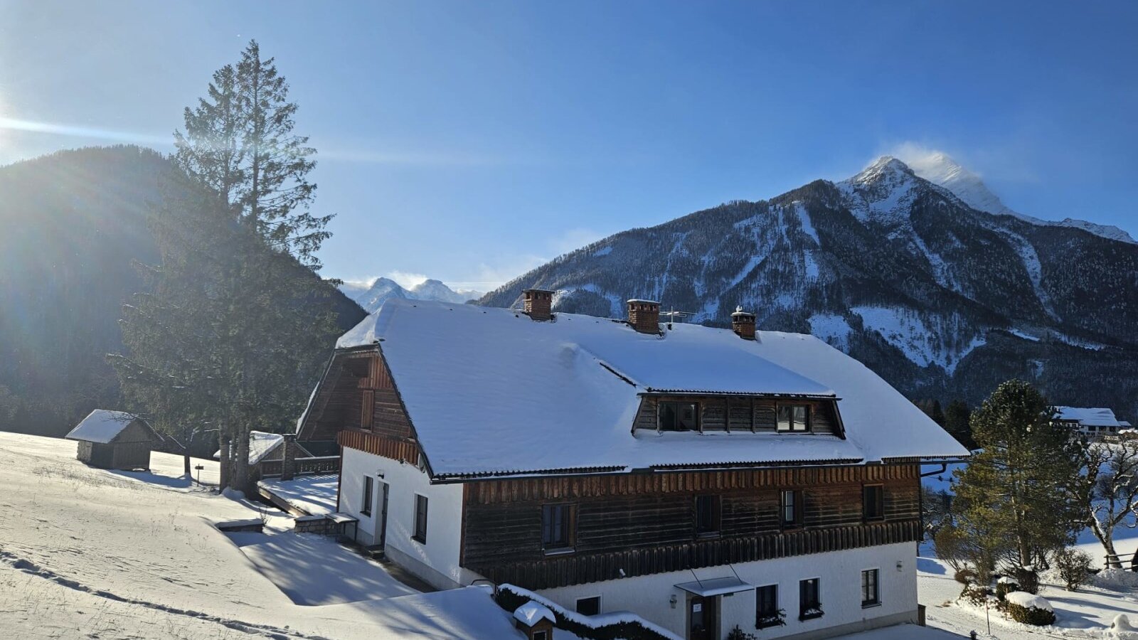The snow-covered farmhouse with a traditional wooden facade and mountain views.
