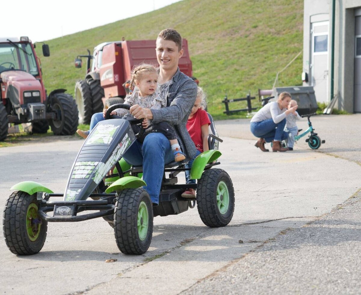 An inviting farm with spacious play areas, fun pedal go-karts for children, and real tractors in the background.