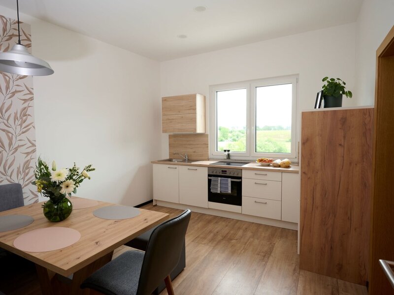 Modern kitchen and dining area in the farm house, featuring a stove, oven, sink, wooden table, and a window with outdoor views.