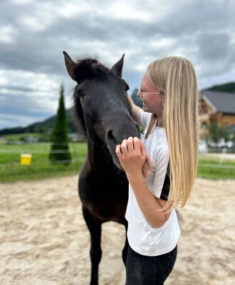 A girl petting a horse on the grounds of the Ap­par­te­ments.