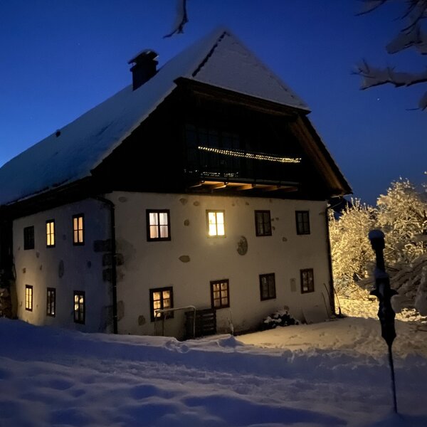 The Farm House illuminated at night during winter, surrounded by snow. The Farm House illuminated at night during winter, surrounded by snow.