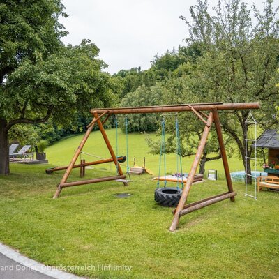 The farmhouse's children's playground with a wooden swing, tire swing, seesaw, and playhouse