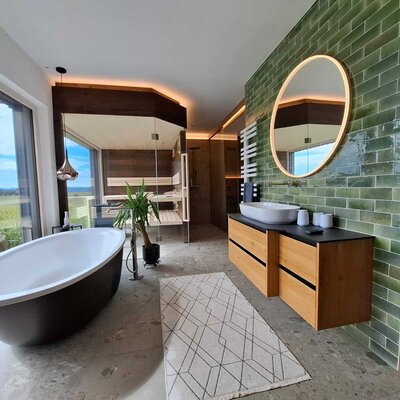 The holiday home's luxurious bathroom featuring a freestanding bathtub, a private sauna, and scenic countryside views.
