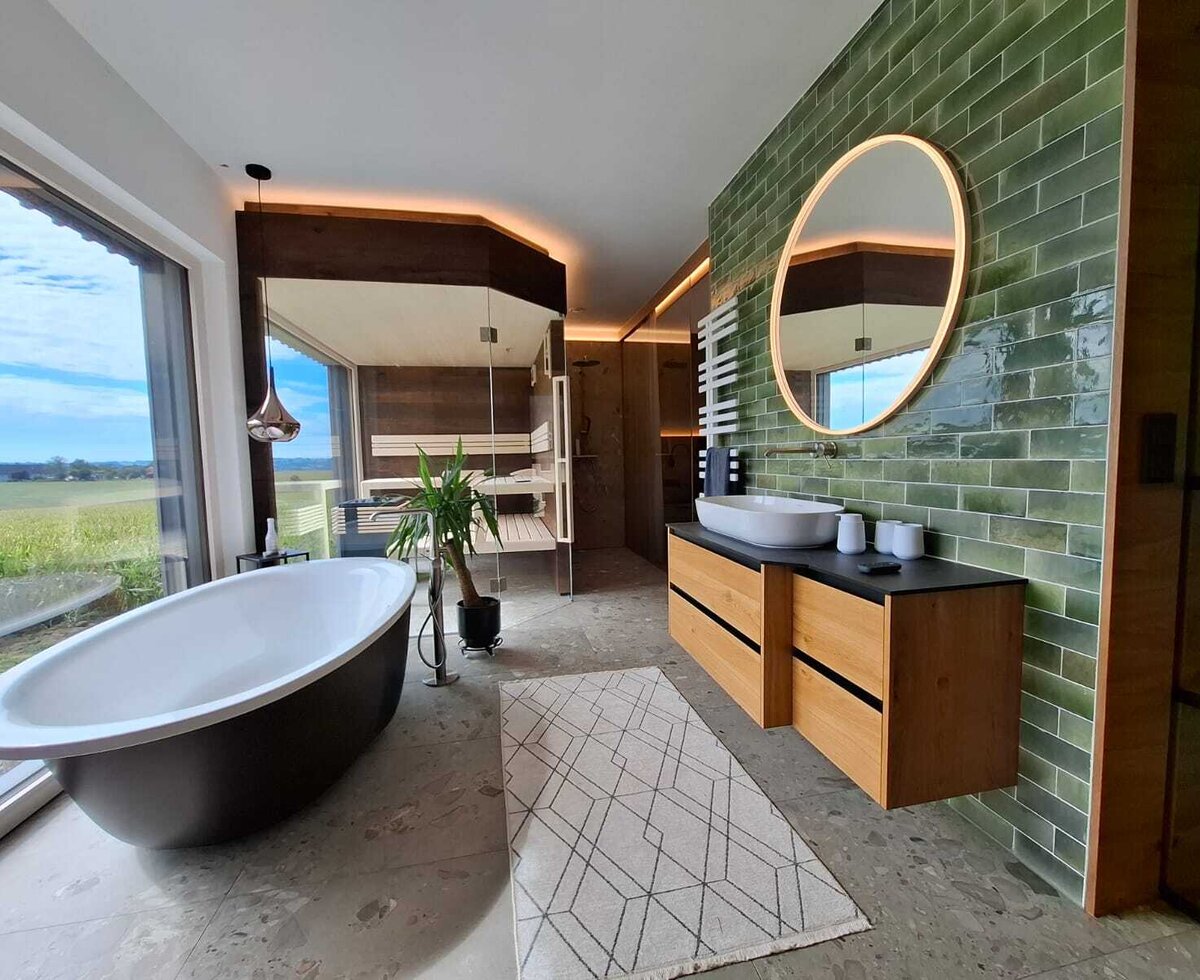 The holiday home's luxurious bathroom featuring a freestanding bathtub, a private sauna, and scenic countryside views.