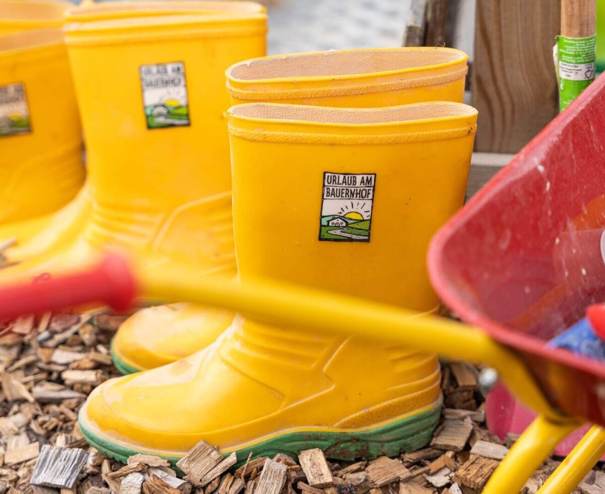 Bright yellow rain boots and a toy wheelbarrow, perfect for little adventurers on the farm.