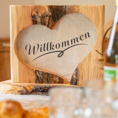 A warm, handcrafted wooden welcome sign greets guests at the farmhouse.