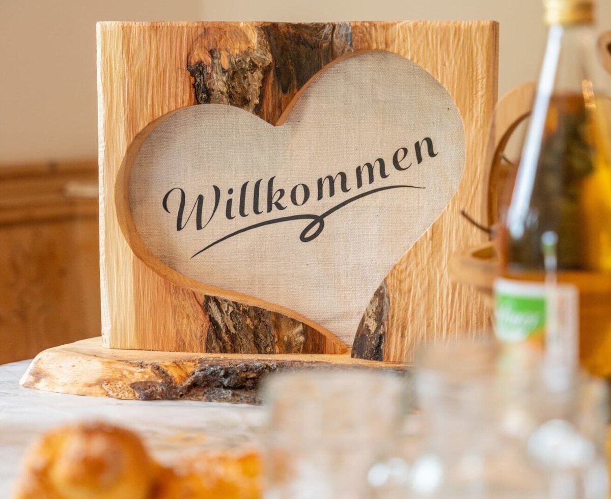 A warm, handcrafted wooden welcome sign greets guests at the farmhouse.