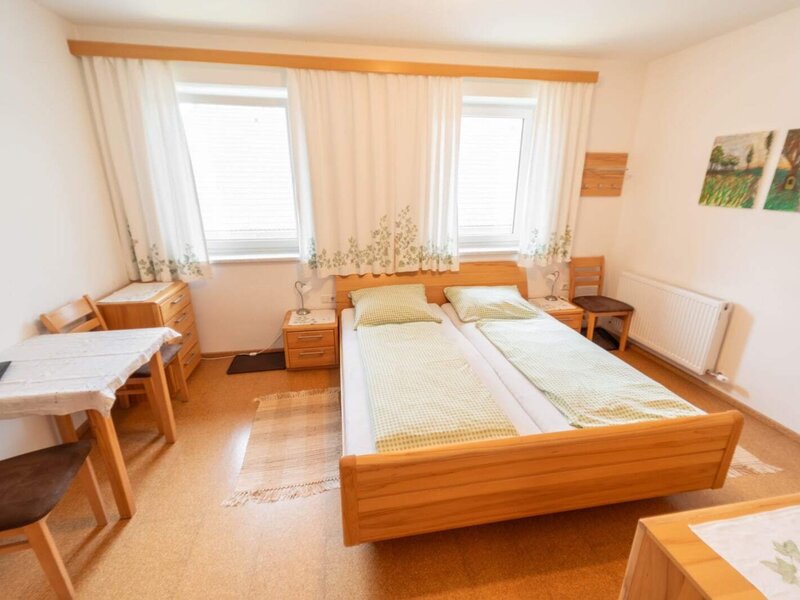A bright double room in the farmhouse with wooden furnishings, a cozy seating area, and pleasant natural light.