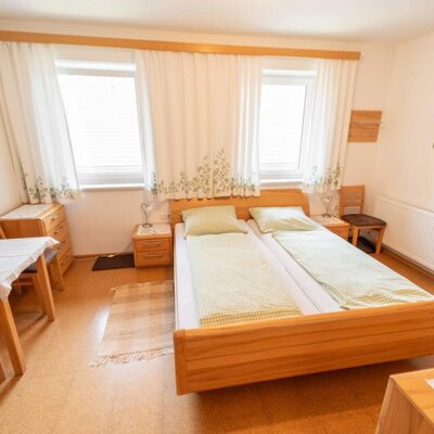 A bright double room in the farmhouse with wooden furnishings, a cozy seating area, and pleasant natural light.