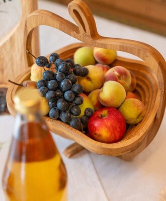 An inviting wooden basket filled with fresh apples, peaches, and grapes at the farmhouse.
