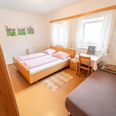 A cozy room in the farmhouse featuring a double bed, an extra bed, and an inviting seating area.