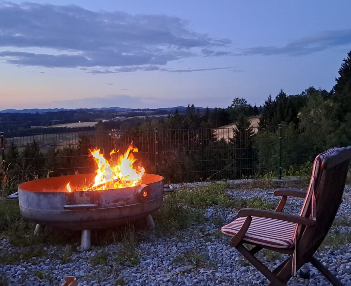 An inviting fire pit with cozy seating and scenic views over the rolling hills at dusk.