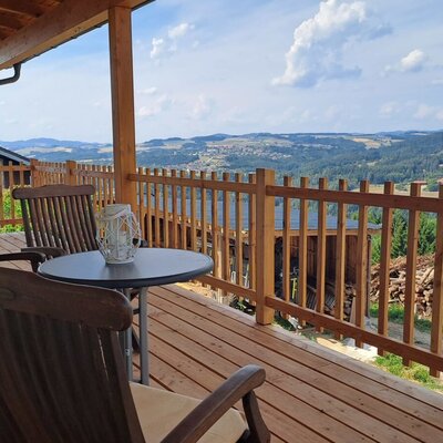 The inviting wooden terrace with cozy seating and a wide, panoramic view over the Mühlviertel landscape.
