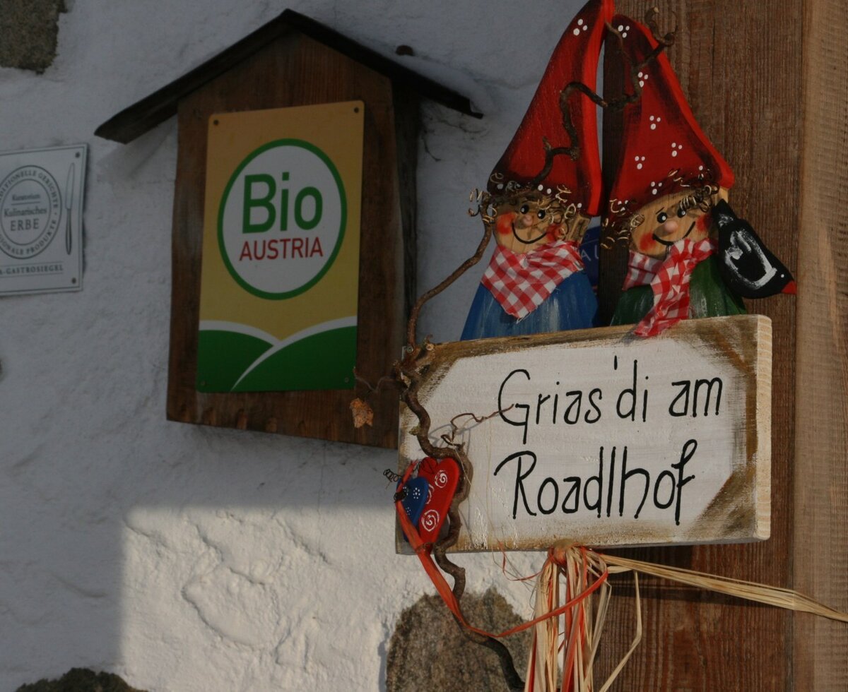The Farm House entrance displays a welcome sign "Grias 'di am Roadlhof" and certifications for "Bio AUSTRIA" and "Kulinarisches Erbe".