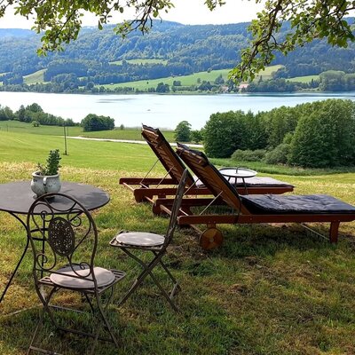 The Farm House offers an outdoor seating area with sun loungers and a fire pit, providing views of the lake and mountains.