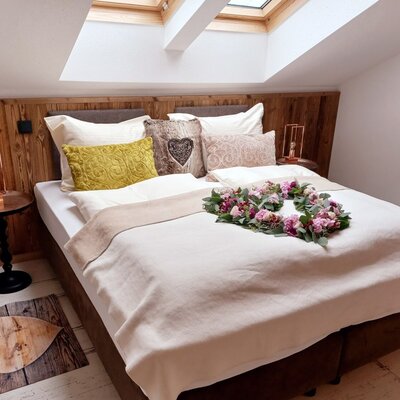 Double bedroom in the Farm House featuring wooden wall paneling, a sloped ceiling with skylights, and bedside tables with lamps.