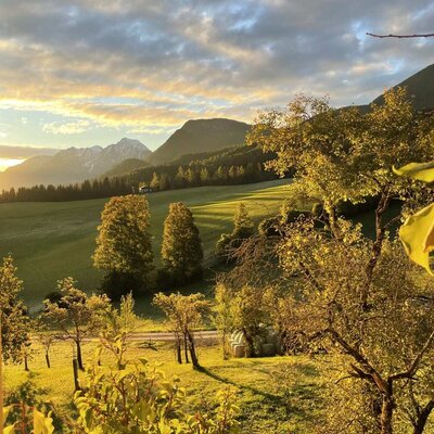 The view from the farmhouse of the spring landscape with blooming fruit trees and snow-capped mountains.
