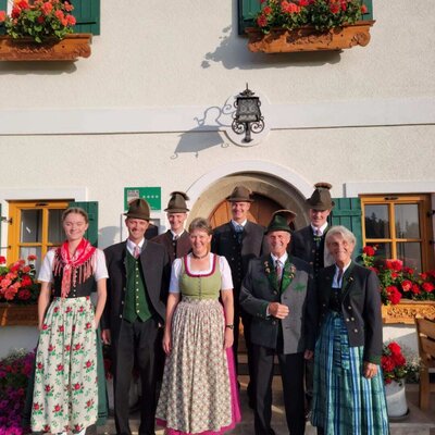 The host family of the 4-star Bauernhof in traditional attire in front of the building.