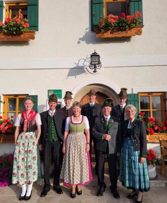 The host family of the 4-star Bauernhof in traditional attire in front of the building.
