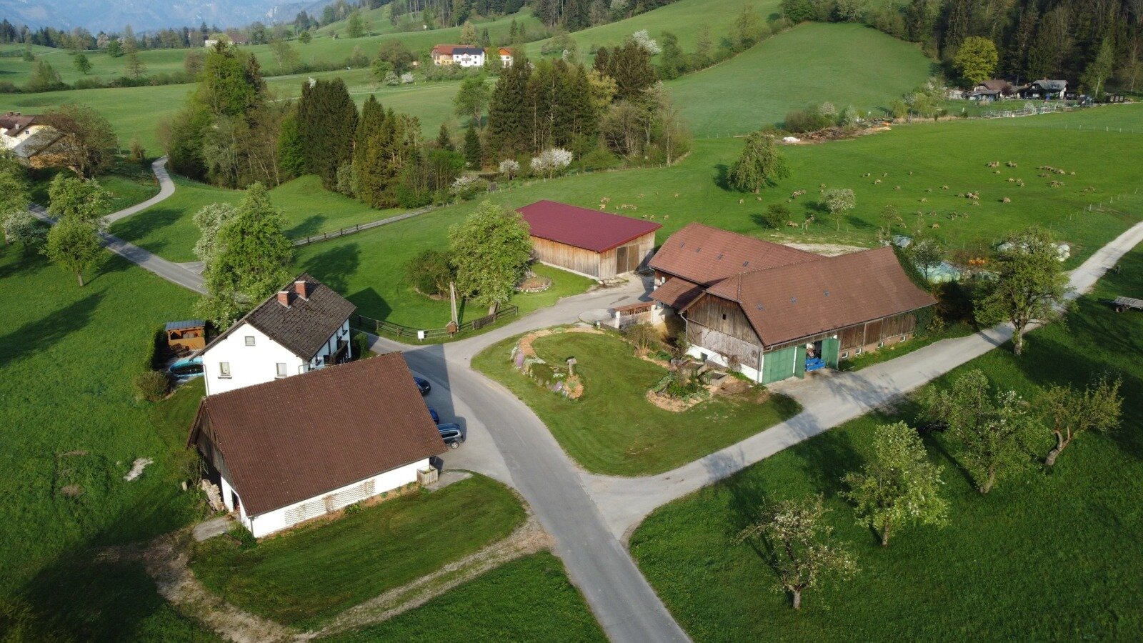 Aerial view of Biohof Grubbauer, a farm with multiple buildings and surrounding green fields.