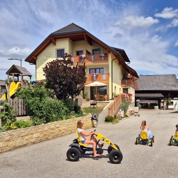 The inviting farmhouse featuring a spacious outdoor play area with go-karts and a children's playground.