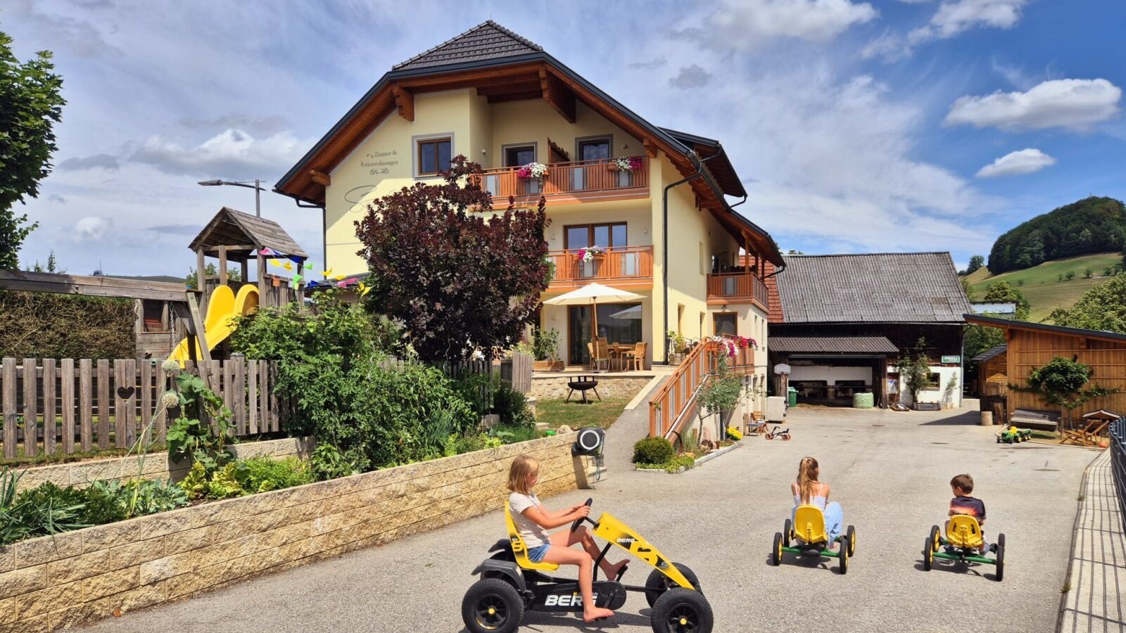 The inviting farmhouse featuring a spacious outdoor play area with go-karts and a children's playground.