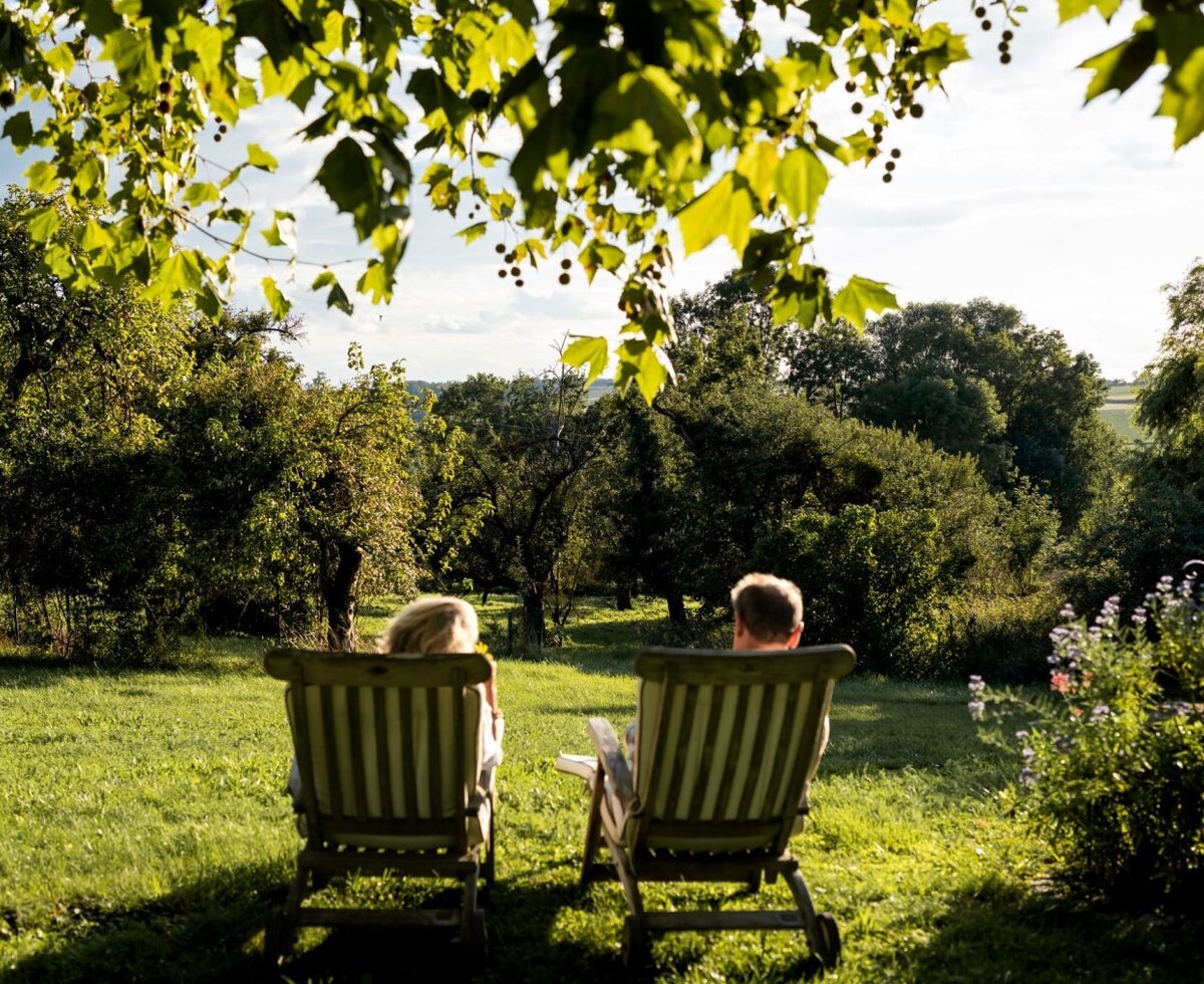 The farmhouse's inviting relaxation garden with comfortable deckchairs under shady trees and views of the lush greenery.