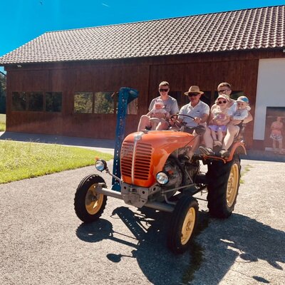 A charming vintage tractor at the farmhouse, inviting guests for a fun ride on a sunny day.