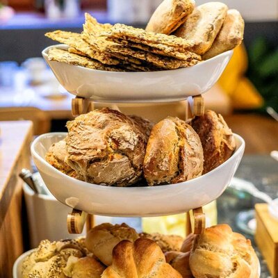 Various types of bread and pastries on a tiered stand, part of the breakfast offering at the farmhouse.