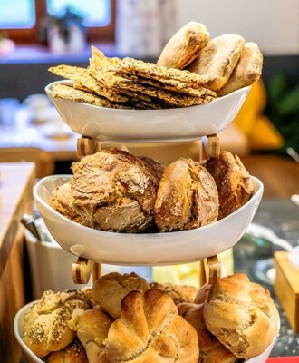 Various types of bread and pastries on a tiered stand, part of the breakfast offering at the farmhouse.