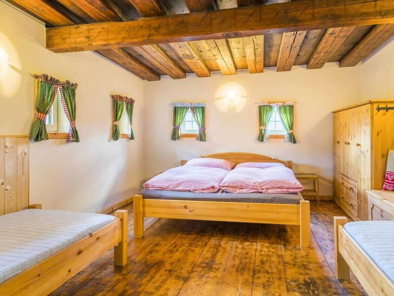 Spacious four-bed room in the farmhouse, featuring a double bed, two single beds, and a wooden beamed ceiling.