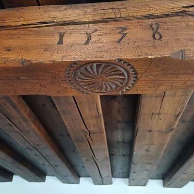 Exposed wooden ceiling beams in the farmhouse feature a carved design and the year 1538.