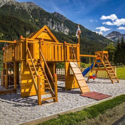The farmhouse offers a children's playground with a wooden structure, slide, swings, and climbing net.