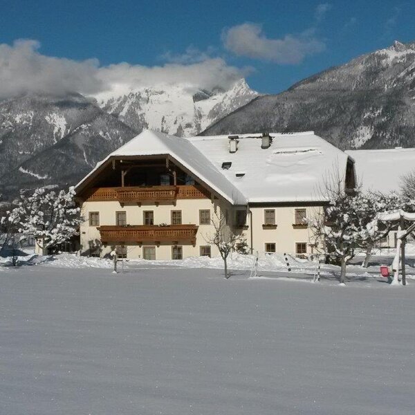 The Farm House exterior in winter, featuring snow-covered roofs, wooden balconies, and a backdrop of snowy mountains. The Farm House exterior in winter, featuring snow-covered roofs, wooden balconies, and a backdrop of snowy mountains.