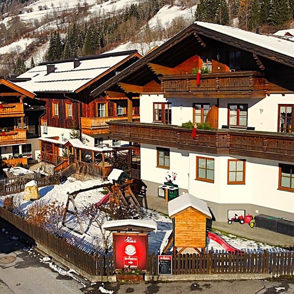 The Bauernhof buildings with balconies and a children's playground including a swing set and slide, set in the snow.