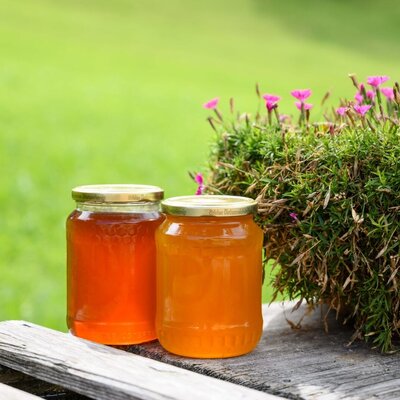 Jars of local honey on a wooden surface, highlighting fresh produce available at the farmhouse.