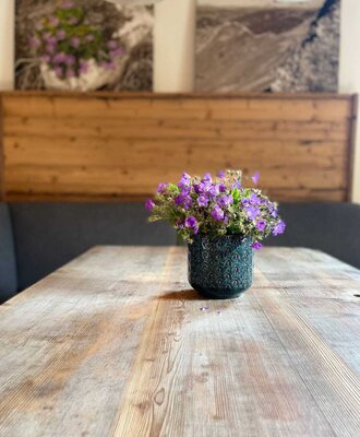 A rustic wooden table in the bed and breakfast, adorned with a charming vase of purple flowers.