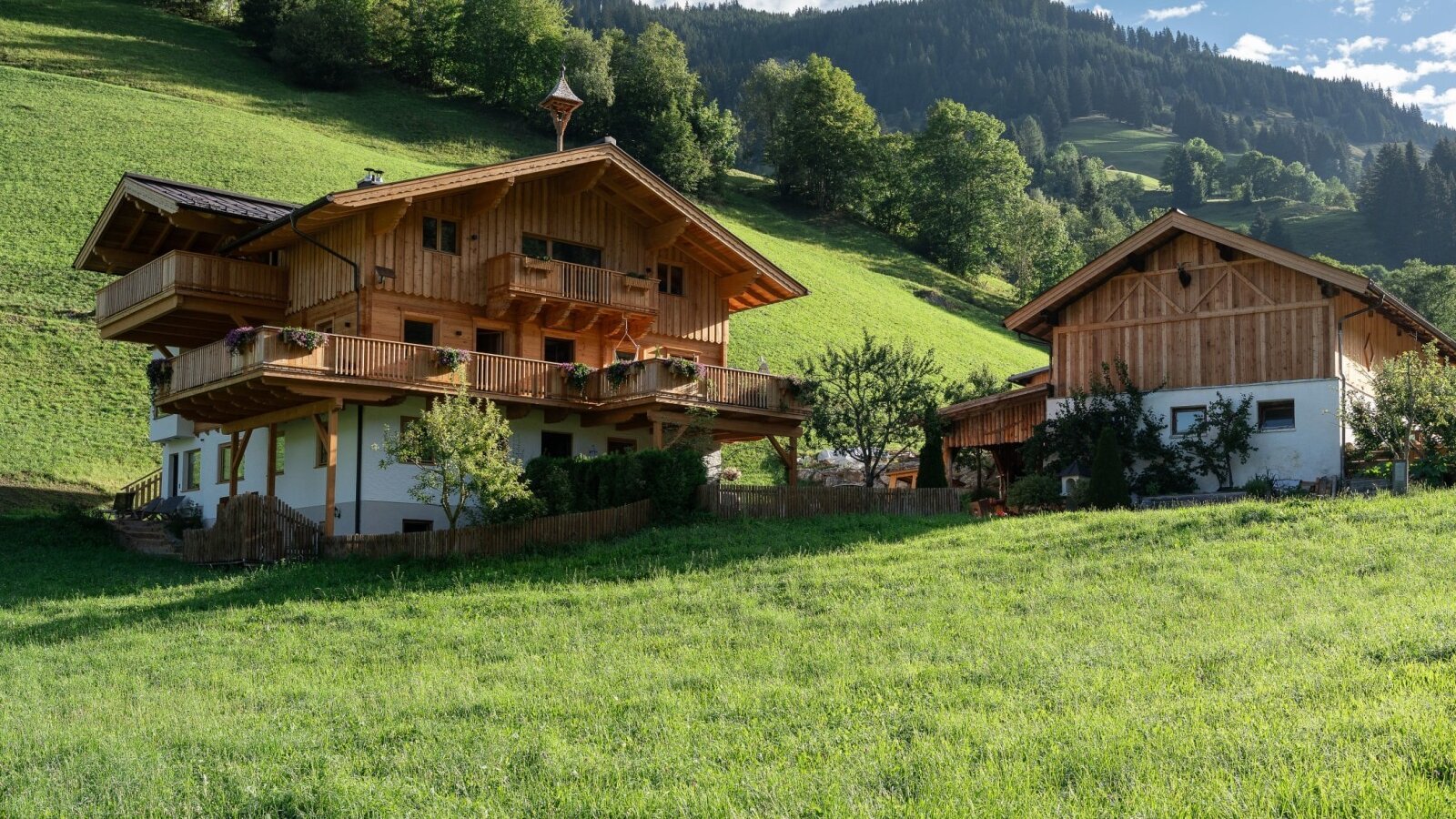 The charming farmstay nestled in a lush green meadow, surrounded by scenic alpine hills.